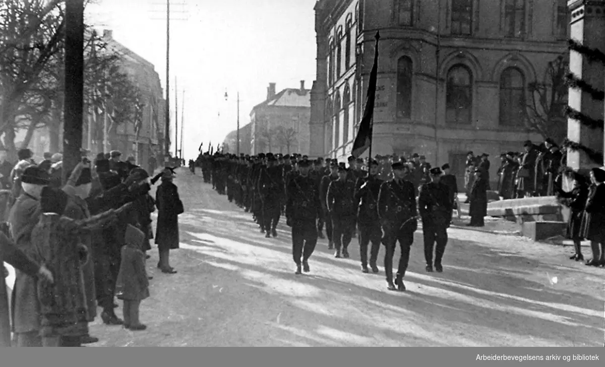 Rikshird marsjerer mens folk langs gaten gjør nazihilsen, Hesselbergs gate i Skien,.1940-45