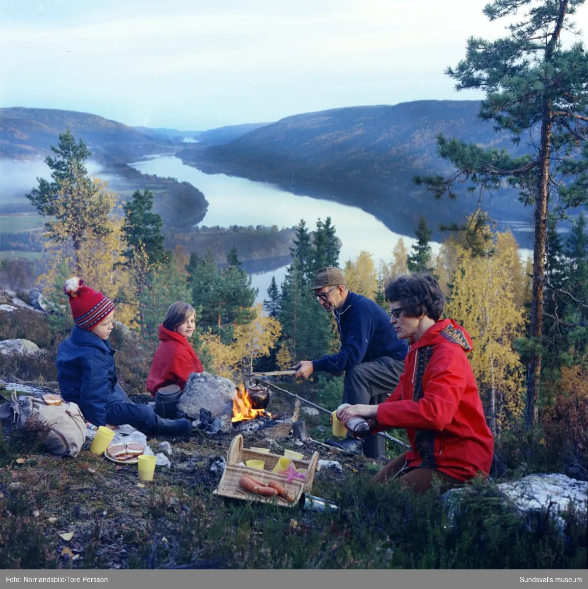 Utsikt från Vättaberget i Liden. En familj kokar kaffe och grillar korv över öppen eld en höstdag 1966.