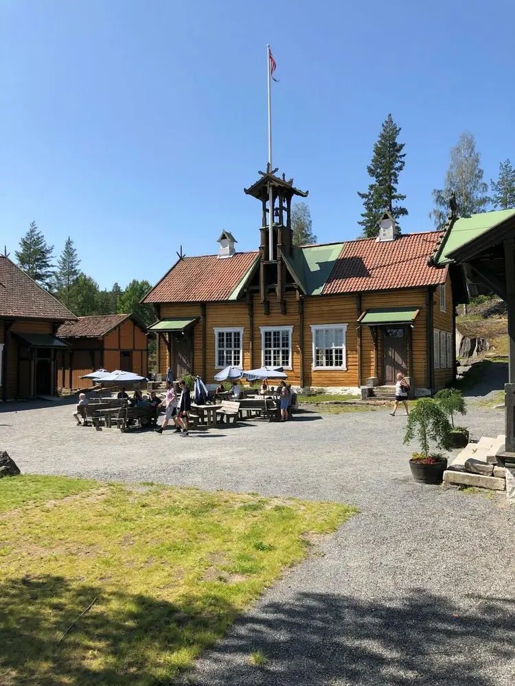 Gjester som sitter på benker en sommerdag ved Sakkerhusene.