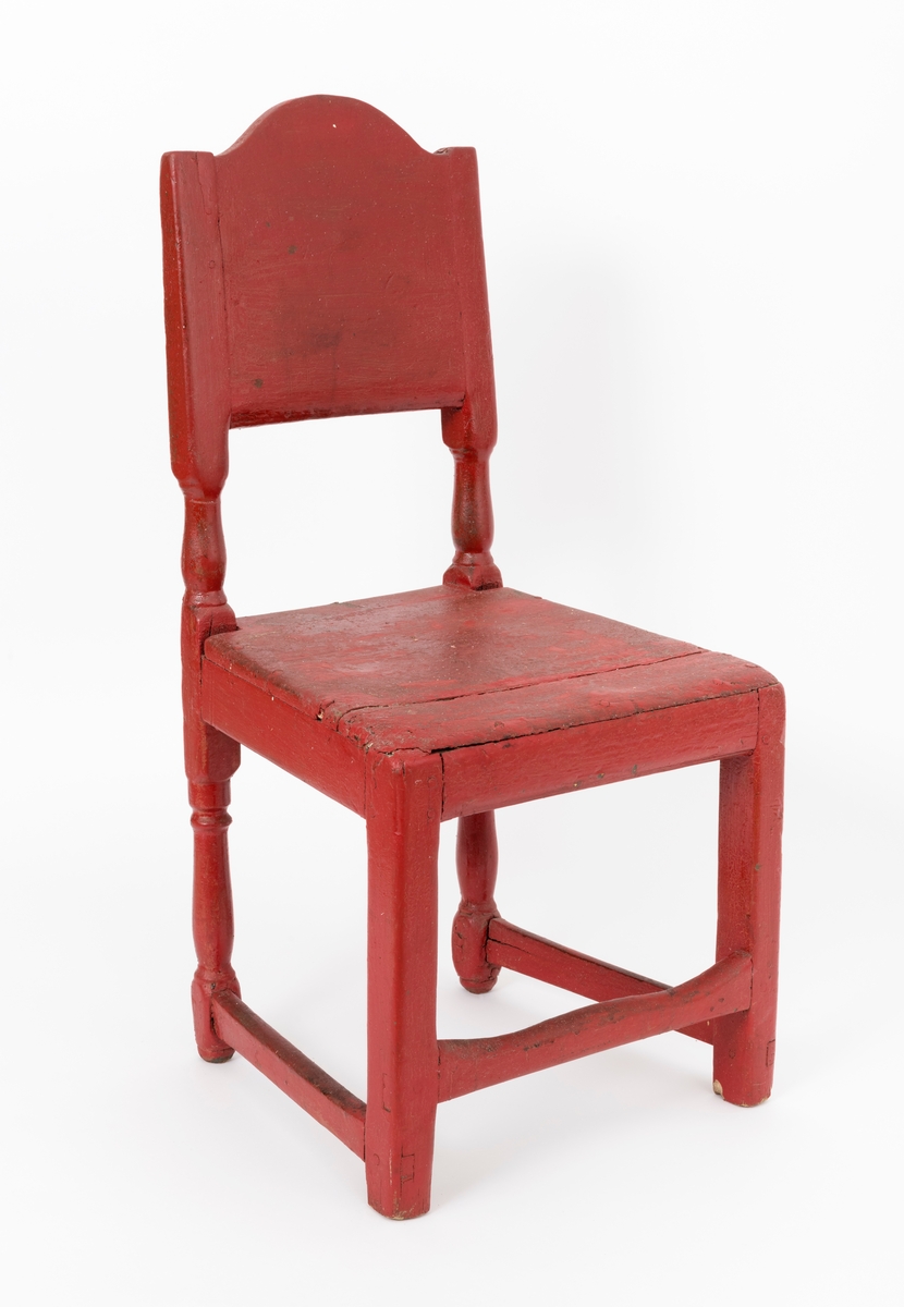 Stol av treverk med ryggstø (rygg) og fire ben. Stolen har fast sete uten stopping. Stolryggen, ryggstøet (ryggen), er svakt skrånende. Treverket er bemalt med rød farge. Stolen er sammenføyd med tapping, spikre og skruer. Setet, som består av to treplater, er spikret fast til sargen og de fremre stolbena. Stolbena foran er rette, mens stolbena bak er dreide. Stolryggen består av en treplate som er felt inn i spor på innsiden av de bakre stolbena. Treplata har en buet profil øverst. Det er tre mellomstykker mellom stolens ben, to på siden og et foran. Mellomstykkene er tappet inn i stolbena. Sidesprossene melllom stolbena har en lengde på 29, 5 centimeter, trestykket mellom stolbena foran er 35 centimeter langt.