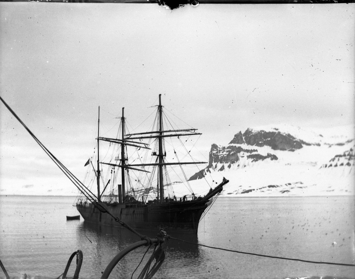 Ett oidentifierat troligen norskt tremastat ångfartyg för ankar vid Spetsbergen. Fotograferat från ett annan fartyg, sannolikt kanonbåten HMS Svensksund. Snöklädda berg i bakgrunden.