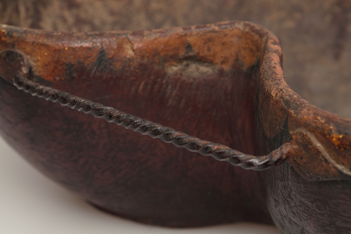 Øltrøisen er uthulet av en bjørkerot, den har tre snodde håndtak av jern og en tut av tre. Den er dekorert med en en tungebord i hvitt og svart.