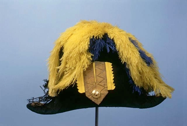 Paraduniform för generallöjtnant i Generalitetet.
Hatt med plym m/1854-59; svart, kantad med bred svart galon, på höger sida knapphål i guldgalon, gul och blå plym.