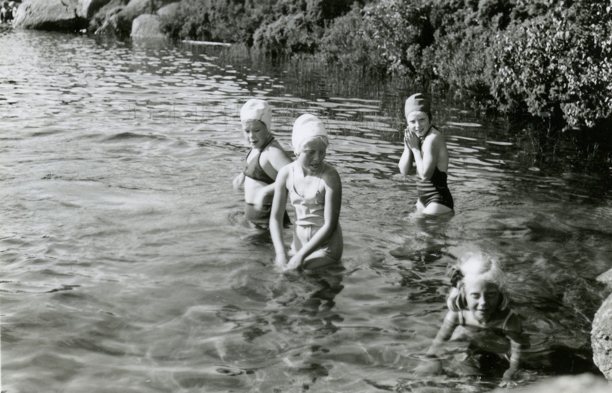 Simskoleundervisning för barn vid Färås tjärns badplats år 1953. Från vänster: okänd flicka, Eva Pettersson (född 1944), okänd flicka samt lillasyster Karin Pettersson (född 1947). Sjön kallas för "Bergsjön".