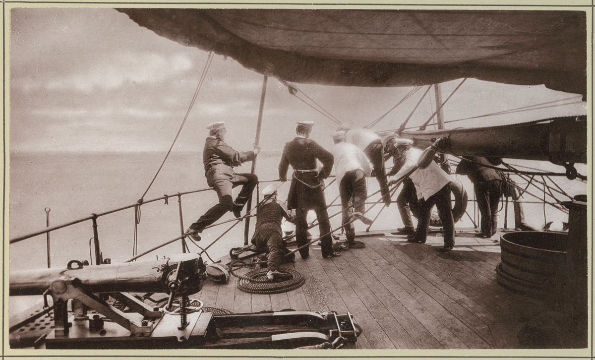 Bilden visar besättningsmedlemmar från korvetten Stosch som sitter på relingen av akterskeppet och håller på att fiska efter hajar.