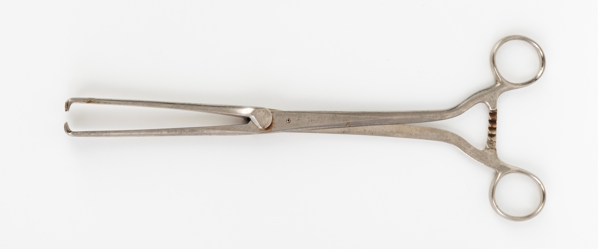 Instrument i stål, en tang (forsellum) som tar tak i livmortappen, Tilhører brikke med 21 ulike instrumenter.