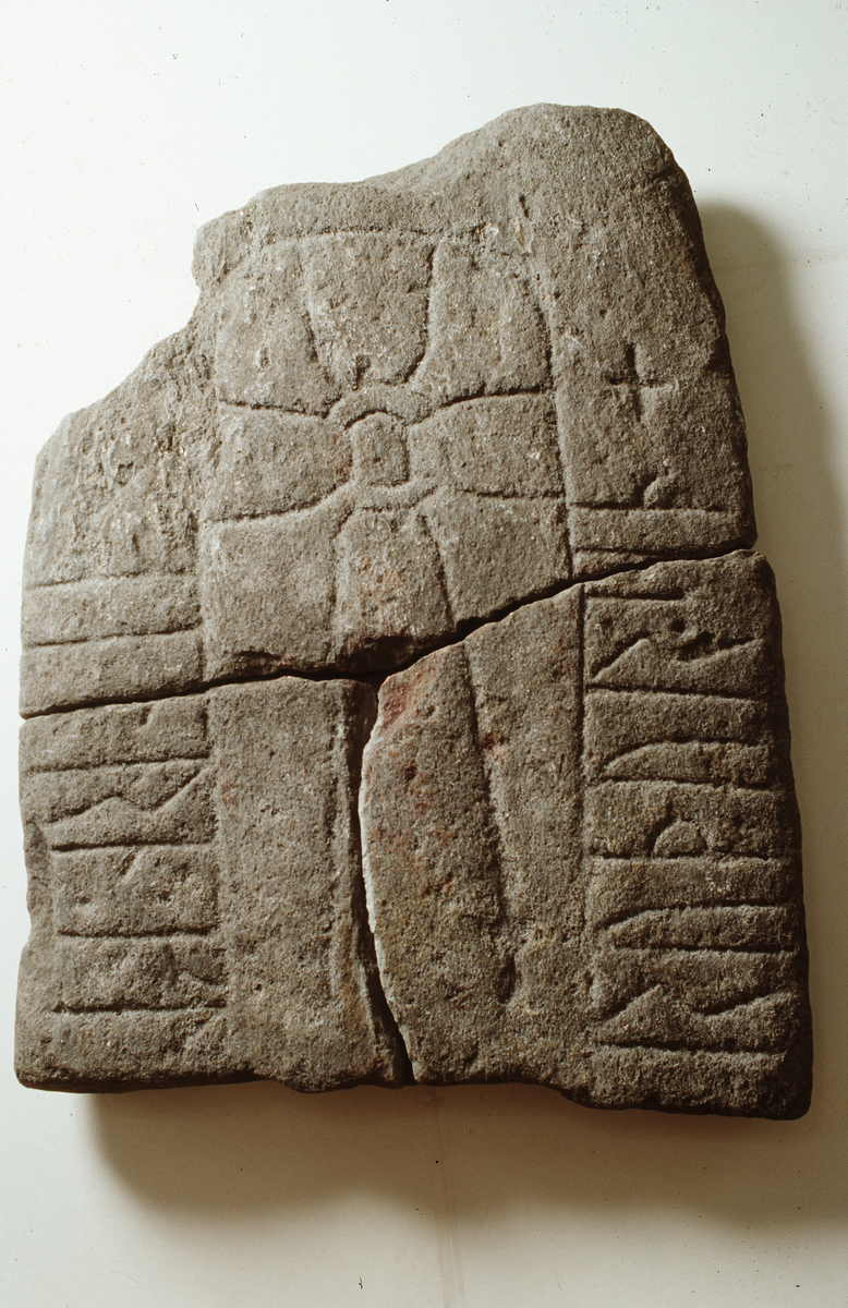 "4451. Stykke av runesten (Njærheim II) av kvartsitisk skifer. Stenfragmentet er 96,5 cm. l. og 67 cm. b., 9,2 cm. tykt. I midten en korsfigur. Langs hver langside en række runer. Paa den ene side staar: **** Paa den anden side: **** Fotografi av stenen er blit sendt til professor Magnus Olsen og ifølge skrivelse fra ham er stenen fra tidlig del av 11. aarhundrede, og runene er de saakaldte jædersk-manske runer. Stenarten er bestemt av lektor Mosgreen."  