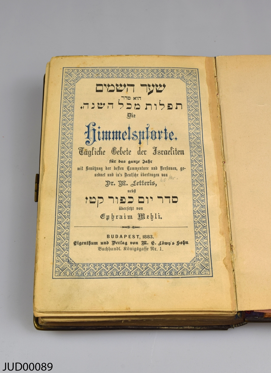 Siddur med hårt benvitt omslag dekorerat med detaljer av mässing och elfenben. Boken är skriven på tyska och hebreiska. Tryckt i Budapest 1883.