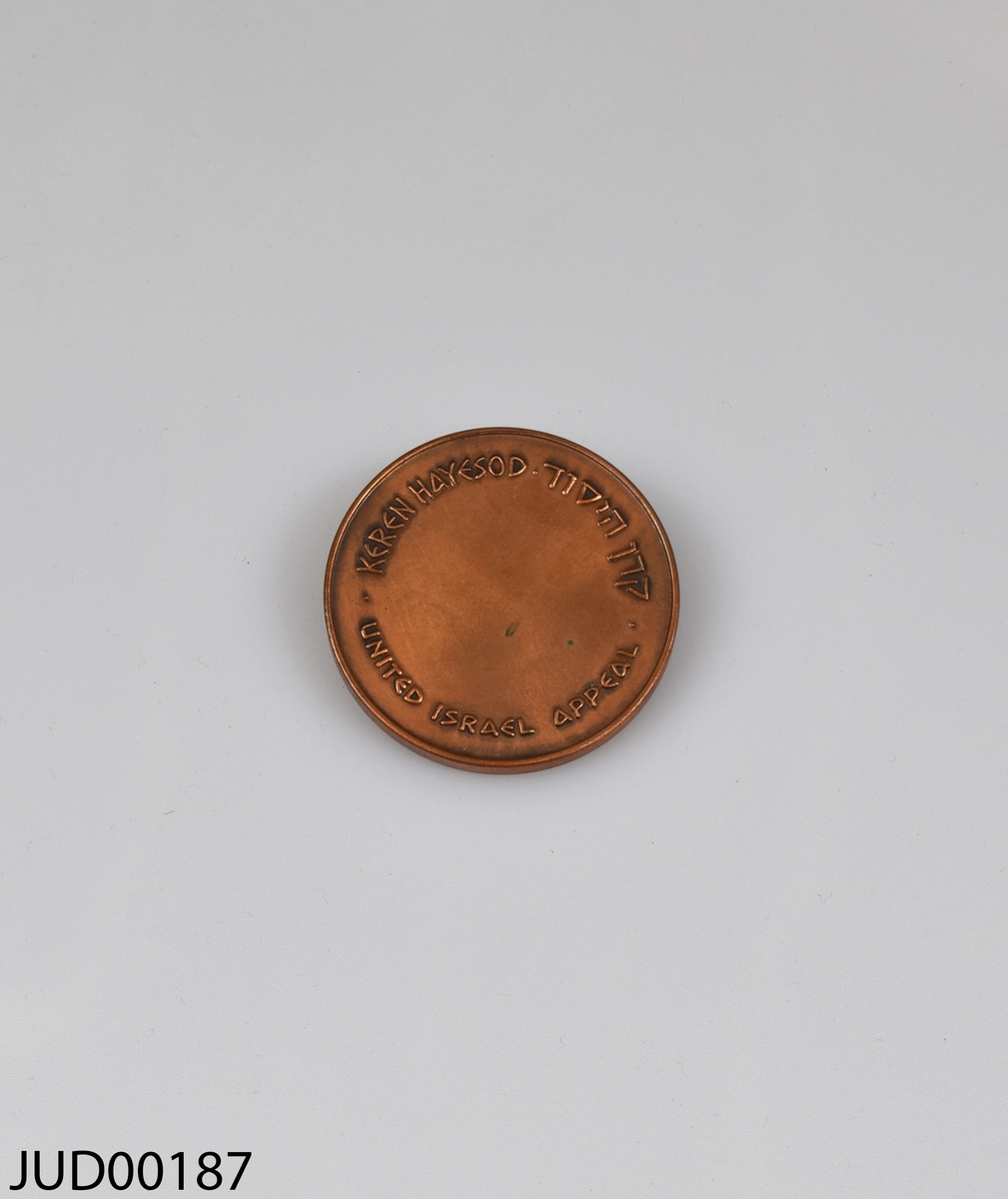 Medalj tillverkad av brons med ett tillhörande ställ av trä. Ena sidan dekorerad med engelsk och hebreisk text, och andra sidan dekorerad med Theodor Herzel i profil samt hebreisk text.
