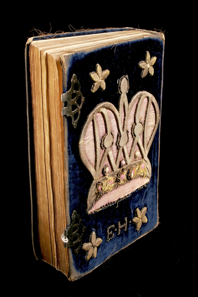 Siddur med pike avot. Boken har ett sammetsomslag med silvertrådsbroderade blommor, en krona och initialerna EH. Två spännen på sidan för att hålla ihop boken. Boken är tryckt på papper i Prag 1867 och är skriven på hebreiska och tyska.