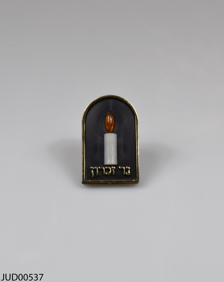 Årslampa (yahrzeit-lampa). Stickkontakt med lampa i form av ett stearinljus och hebreisk text i guld.