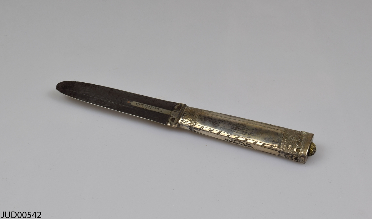 Omskärelsekniv med tillhörande etui. Kniven är tillverkad av silver och är dekorerad med ristade blommor. Etuiet är tillverkat av trä och därefter klätt utvändigt med läder, och invändigt med brun sammet.