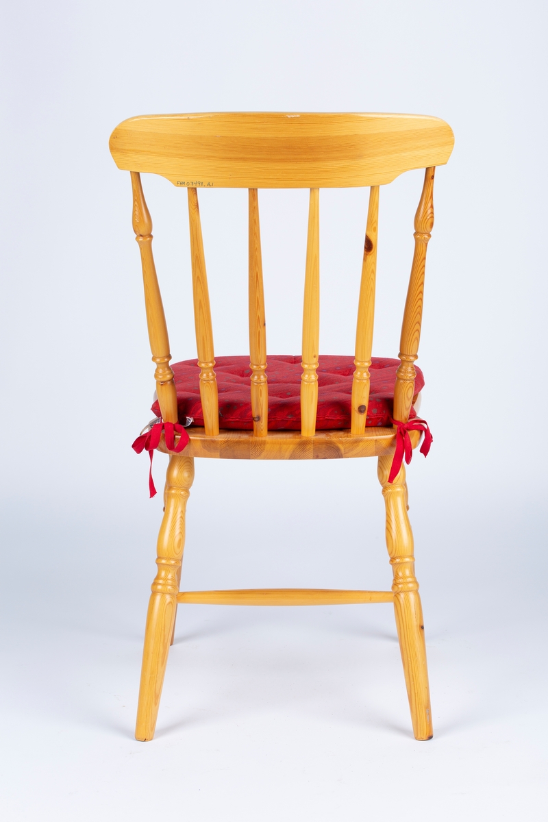 Trestol med dreide ben og ryggspiler. Skumgummipute med rødt trekk hører til.
