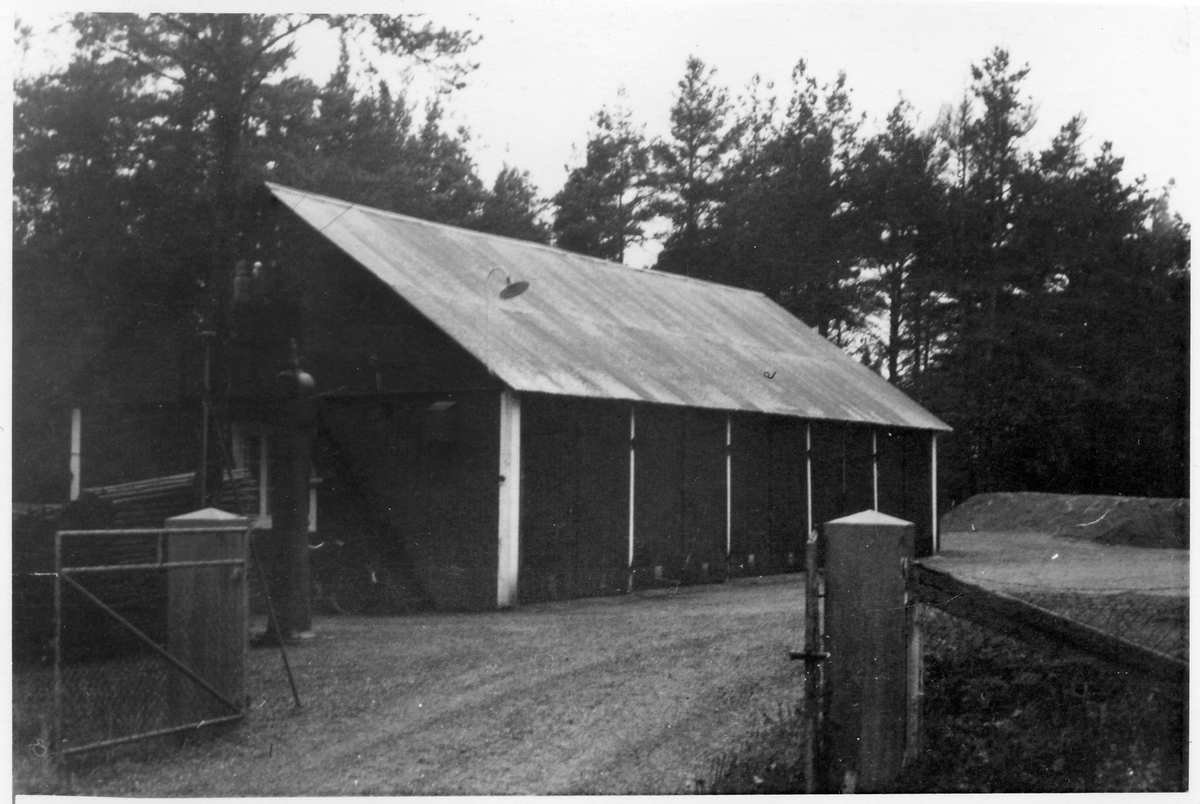 Vägstation B4, Knivsta, filial Vassunda. Garagebyggnad, innanför stängsel med grind. Bensinpump (drivmedelspump).