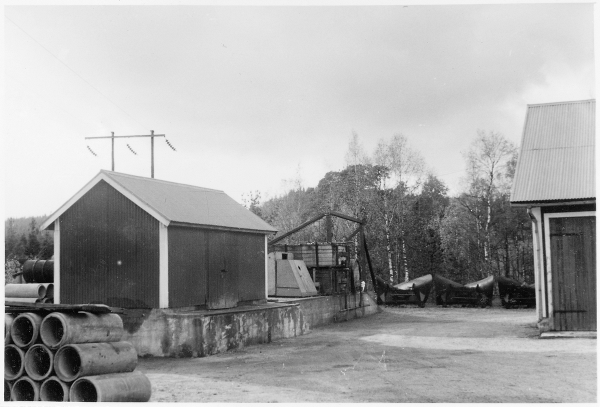 Vägstation N3, Kvibille, filial Torup. Förrådsbyggnad med lastbrygga. Luttunna, med lyftanordning för att lyfta upp den på lastbilsflak. Spetsplogar. Upplag av cementrör.