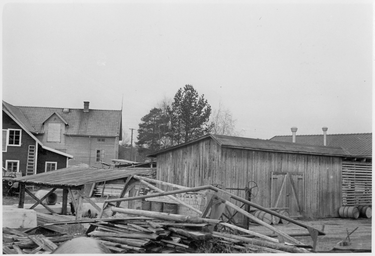 Vägstation Z5, Sveg, filial Ytterhogdal. Förrådsbyggnader. Upplag av trävirke, bränslefat. Vägsladd. Bostadshus i bakgrunden.