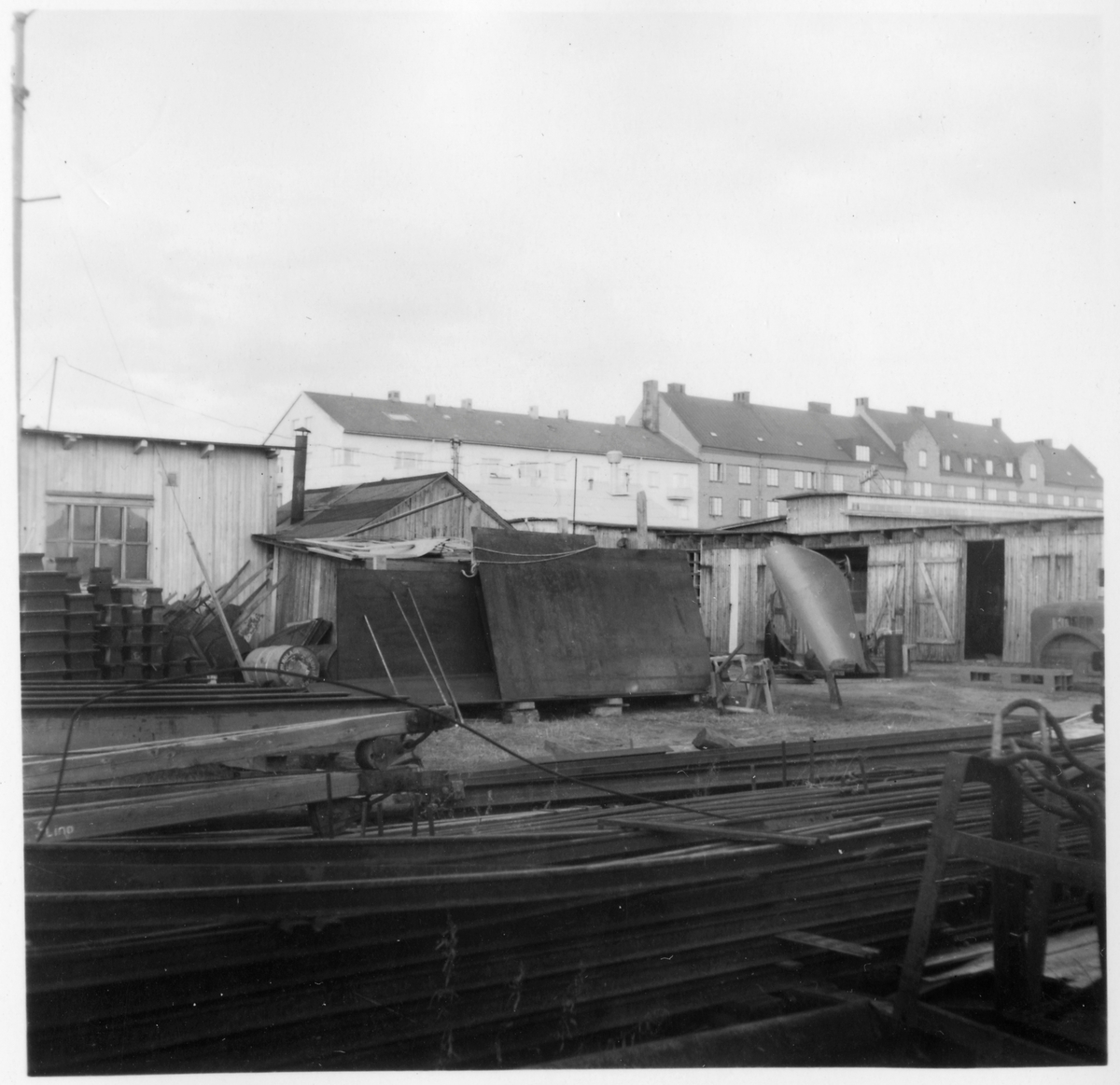 Kvarteret Stören, Luleå. Förrådsbyggnader. Upplag av diverse materiel. I bakgrunden bostadshus, bland bostadshuset (till vänster) Bostadsrättsföreningen Sillen, uppförd 1939.
