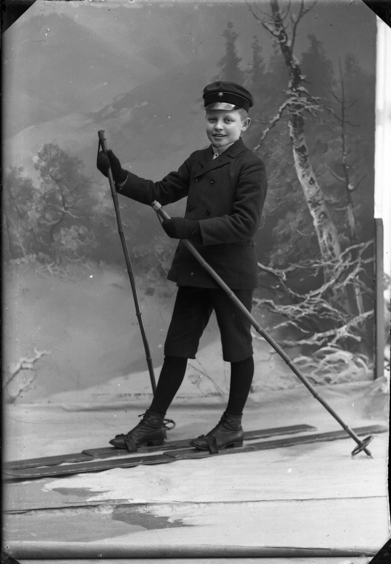 En pojke på skidor mot en vintrig fond.