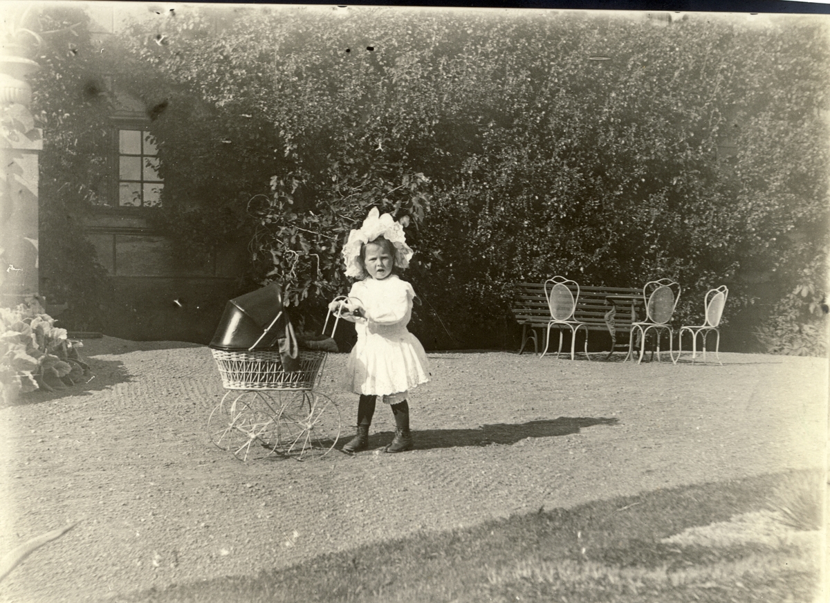 Mimi Egeberg med dukkevogn. Fotografert i parken på Bogstad gård sommeren 1909.