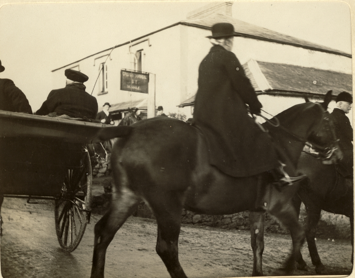 Jegere til hest på vei ut fra Abergavenny i Wales for å delta i jakten "The Meet". Forrest rir Mrs. Cottrell. I kjøretøyet til venstre sitter en eldre mann. Fotografert 1913.