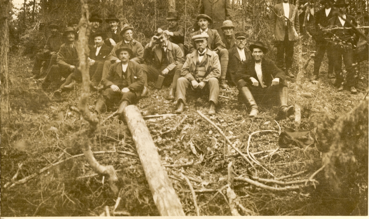 Tømmerfløtere og antagelig funksjonærer holder pause under tømmerfløtingen. Ukjent sted. Fotografert 1918.