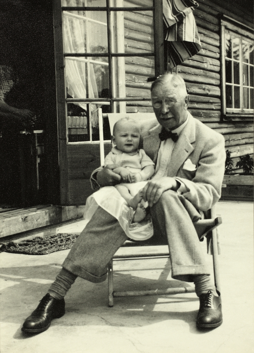 Westye Parr Egeberg med gudsønnen Westye Ferdinand Egeberg på fanget. Fotografert i 1949 på verandaen til Westye Ferdinands hjem i Austmarka, Kongsvinger.