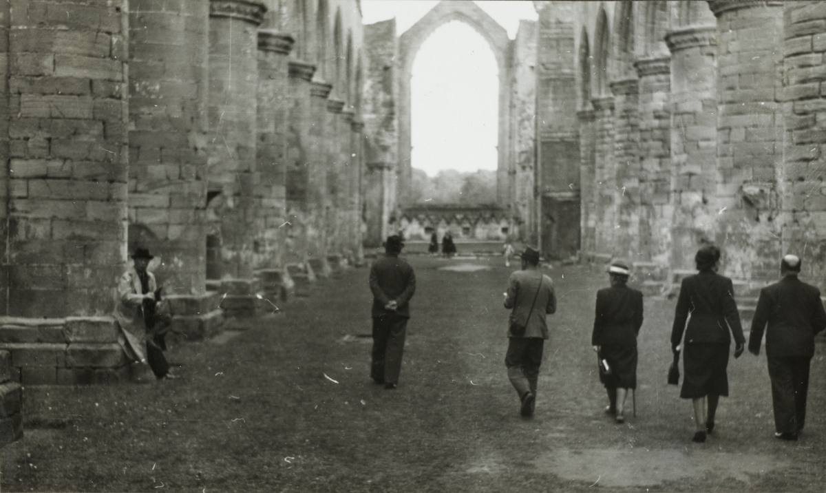To kvinner og tre menn, bl.a. Thomas og Benedicte Fearnley, går gjennom ruinene til Fountains Abbey i North Yorkshire i England.