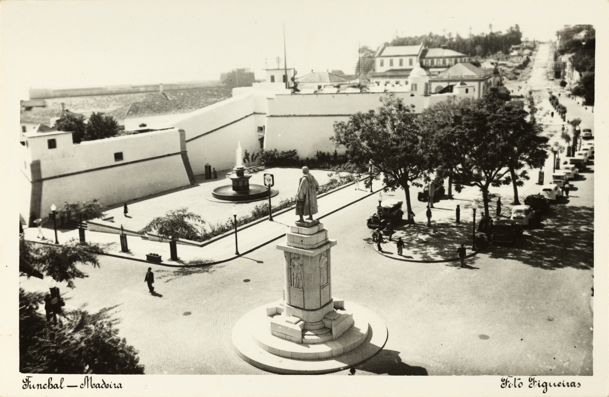 Postkort med motiv fra byen Funchal på Madeira. Blant annet et torg med statue og fontene. Til høyre en boulevard. Kjøpt under reise i 1953.