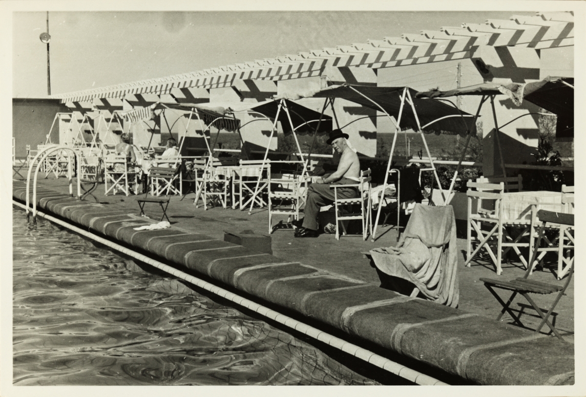 Fra kanten av et svømmebasseng, trolig ved hotell på Tenerife. Til høyre for midten sitter mann med hatt (Westye Egeberg?). Antagelig fotografert under cruise i 1953.