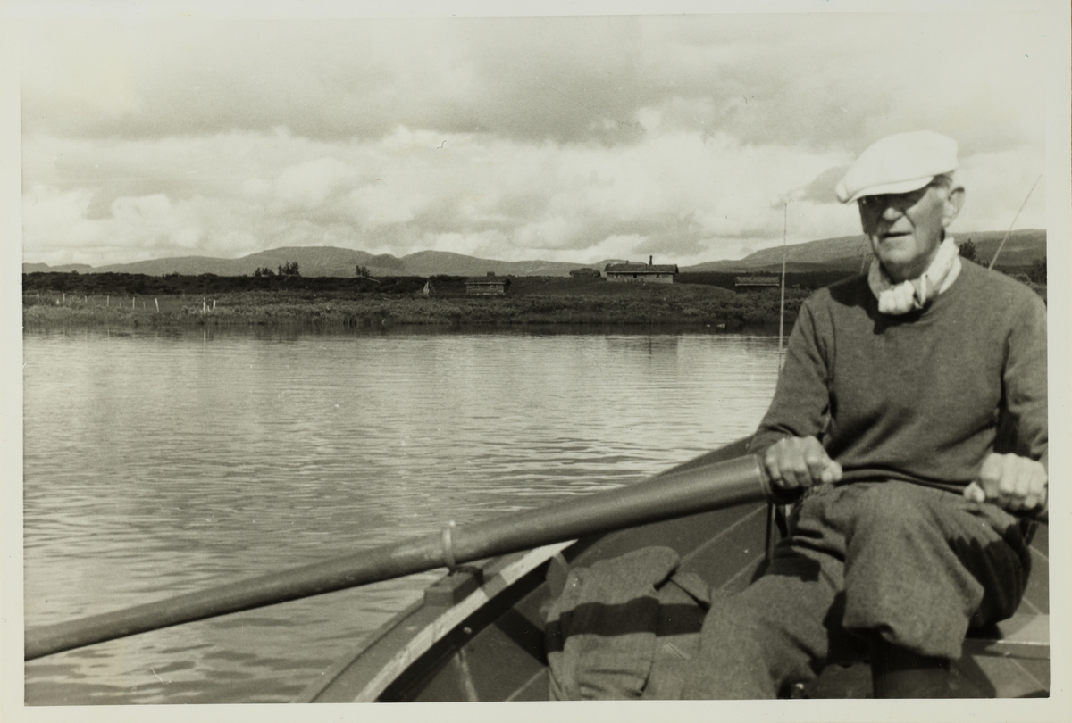 Aksel Hansen ror Westye Egeberg til hytte, antagelig over Revsjøen i Gausdal, Oppland. Fotografert 1953.