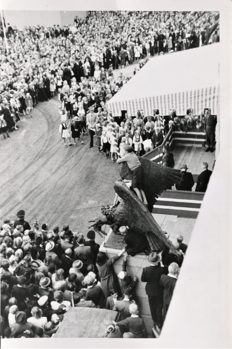 Norges Forsvarssjef kronprins Olav besøkte Haugesund Olsokdagen den 27. juli 1945. Her taler han til folkemassene fra scenen på Rådhustrappene. Bronseørnene foran Rådhuset ble også brukt som utkikksplass.
