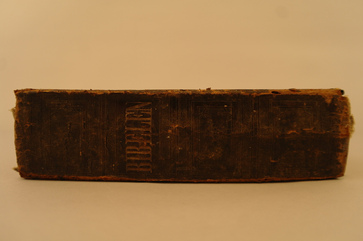 Bok: Bibelen. Det Britiske og Udenlandske Bibelselskab. Svart bokomslag med metallbeslag rundt kantane og en metallspenne for å lukke boken.