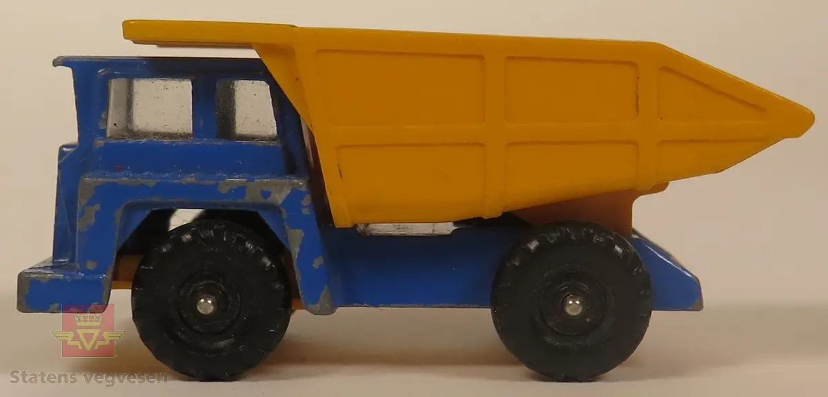 Hovedsakelig blå modell med gult lasteplan. Den er hovedsakelig laget av metall og lasteplanet er laget av plast. Skala 1:74.