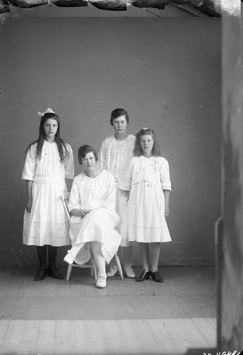 Fyra flickor/unga kvinnor i ljusa klänningar och de två yngre med rosett i håret. De är syskonen Svea, Gerda, Elsa och Elly Andersson från Åsa.