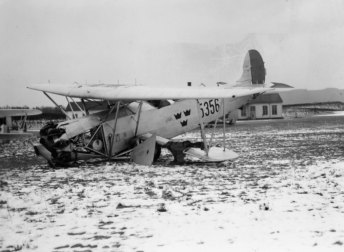 Ett havererat flygplan J 3, Fokker C.V-D, nummer 5356 ligger på ett flygfält. Vintertid, 1930-tal.