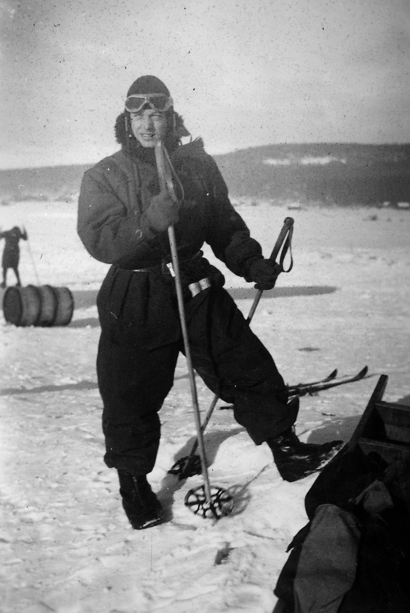 Militäre flygaren Verner Tornberg står i flygdräkt med skidstavar i hand på ett fält. 1930-tal.