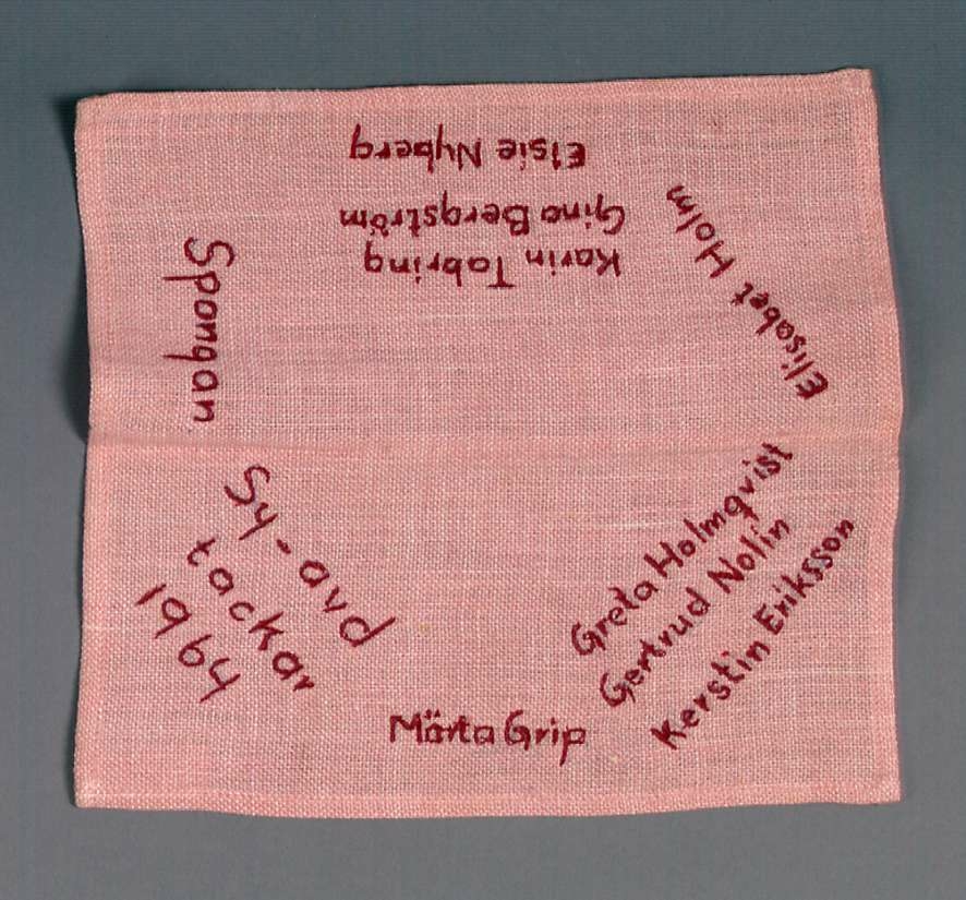 Duk av rosa-vitt linne med broderade namn i rött.