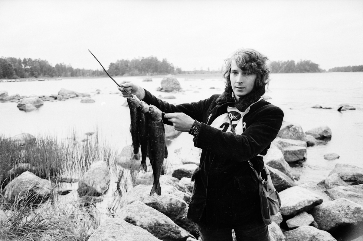 Ung man visar upp sin fångst vid fisketävling i Storforsen, Dalälven
