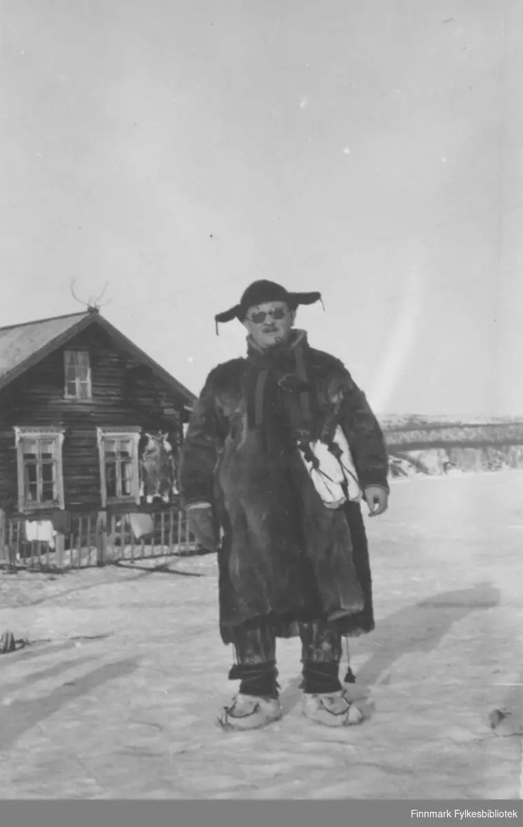 Aksel Konrad Mikkola kledd i pesk og skaller utenfor "gamlestua" på eiendommen Nordmannseng. Eiendommen ligger ved kirka i Neiden.