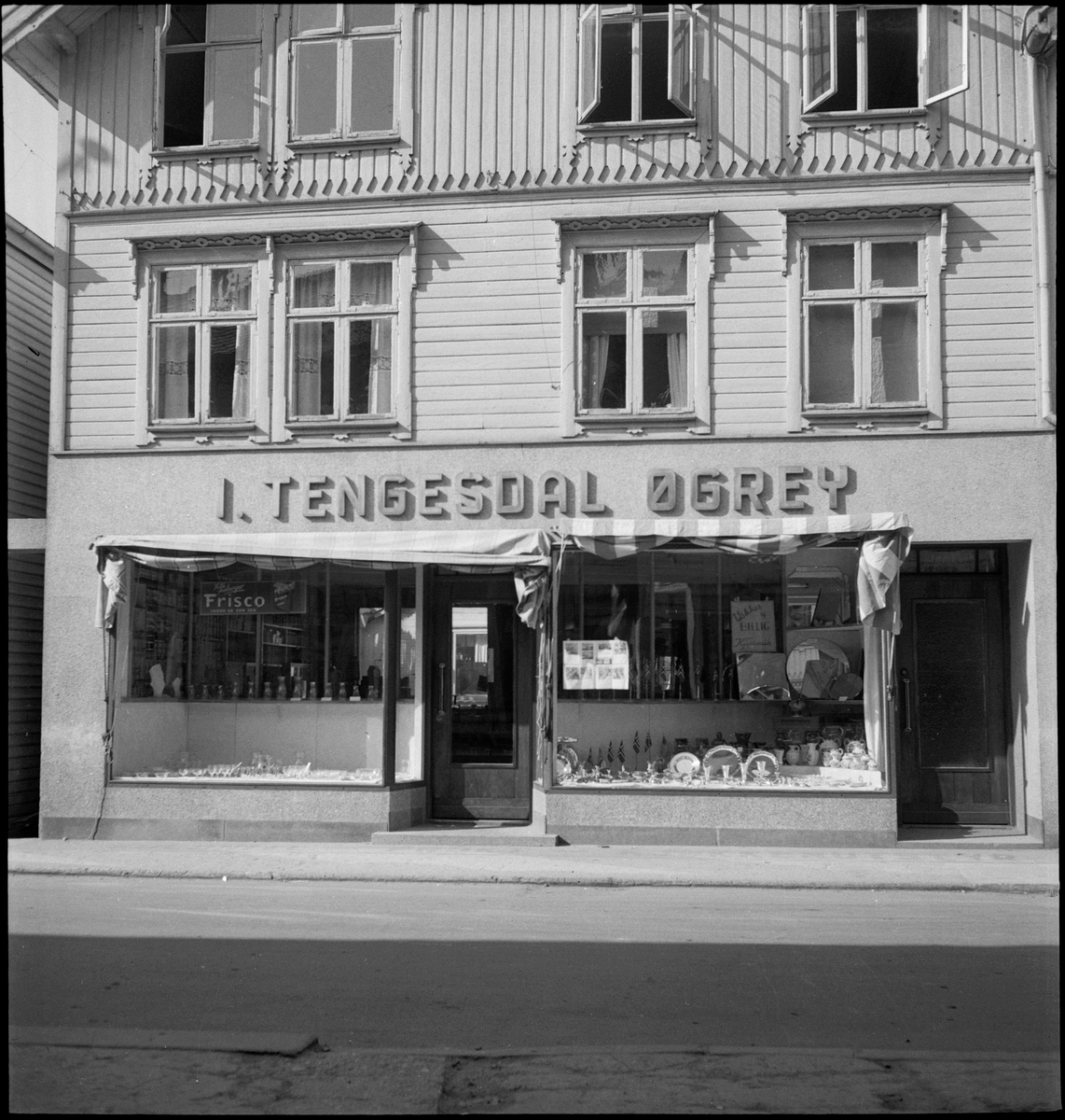 Kjøkkenbutikken "I. Tengesdal Øgrey" i Egersund. Det er glass, keramikk, serveringsfat og flagg i utstillingsviduene.