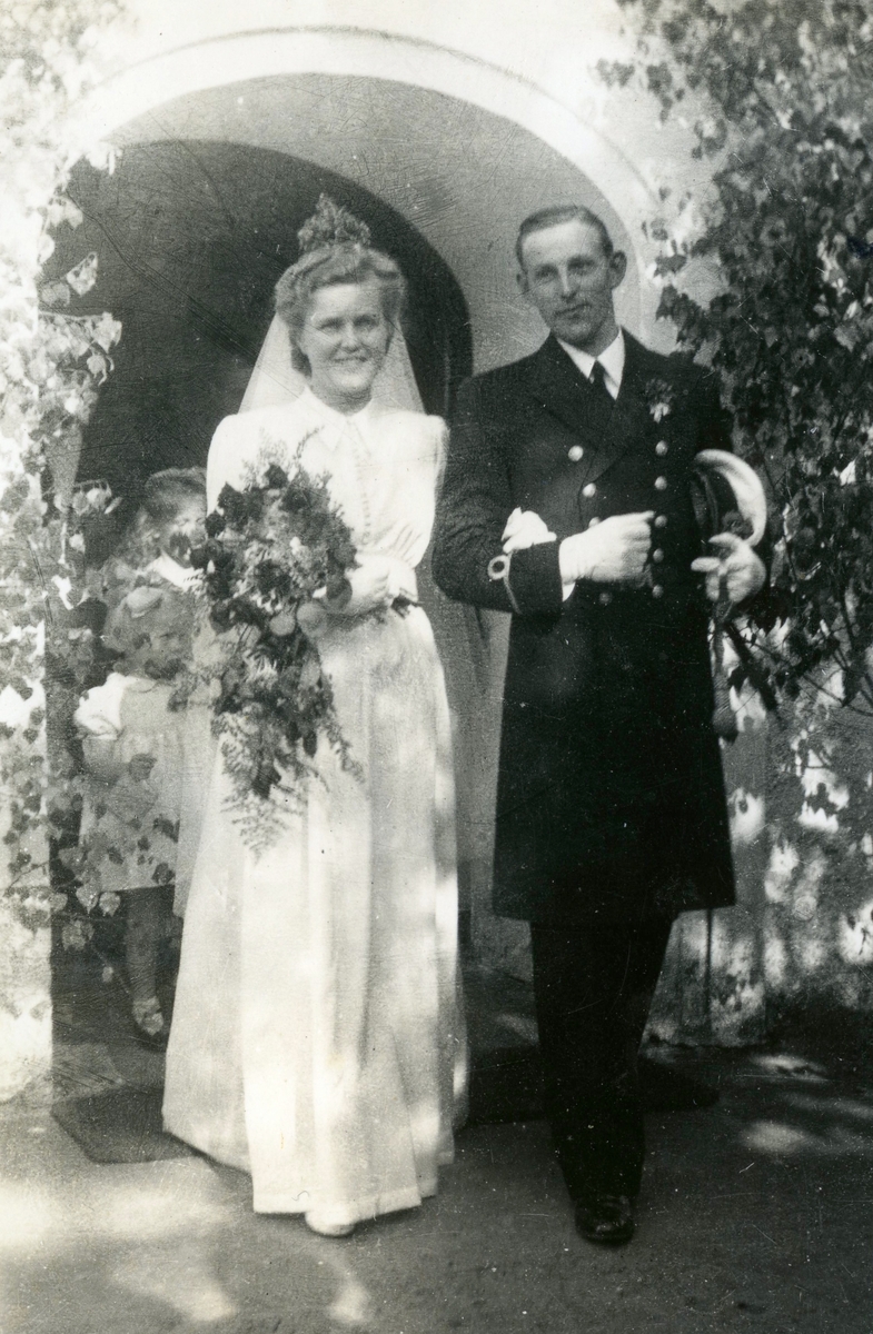 Bröllop mellan Nellie Gustafsson (1919 - 1993) och Eivind "Eje" Kullbring (1918 - 1996) som vigdes i Kållereds kyrka 1942-06-23. Paret står i ett valv utanför kyrkan. Relaterade motiv: A2839 - A2840.