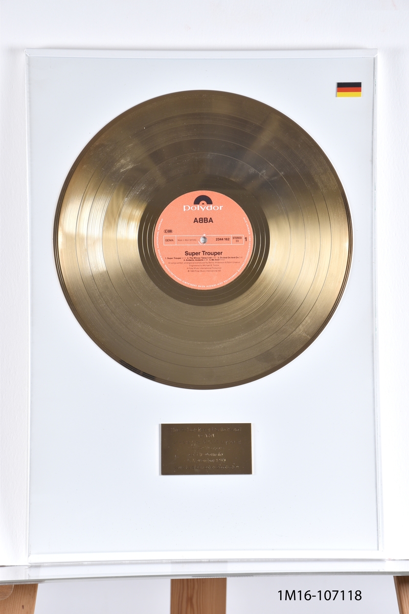Guldskiva utfärdat till ABBA för albumet Super Trouper för mer än 250 000 sålda exemplar i Tyskland, 5 november 1980. Utfärdat av Deutsche Grammophon Geselleschaft. Guldskiva mot vit bakgrund. Plakett under skiva. Tysk flagga i över högra hörnet.