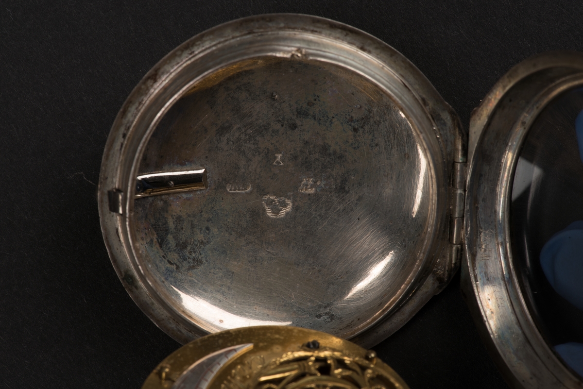 Runt fickur med spindelverk. 
Boetten är tillverkad av silver och locket av glas. Den är stämplad på insidan med: E W (Erik Wellenius), Norrköpings stadsstämpel samt årsstämpel Y (1781). Boetten är försedd med en hållare för klockkedja.
Den vita urtavlan av emalj har svarta romerska siffror samt markeringar för minuter. Uppdraget sitter vid IIII. Det finns en tim- och en minutvisare, de är tillverkade i gulmetall.
Verket är graverat med: Erik Wellenius Norrköping No 306.