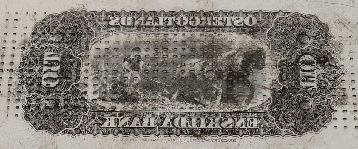 Tryckplåt för tolv 10-kronors-sedlar för Östergötlands Enskilda Bank. Motivet är två hästar som drar en plog med en man på plogen och var sedelns baksida. Ett skruvhål i varje hörn. Framsidan är slät och glansig. Baksidan är lite rostig och har många märken i form av fyrkanter, streck och cirklar.