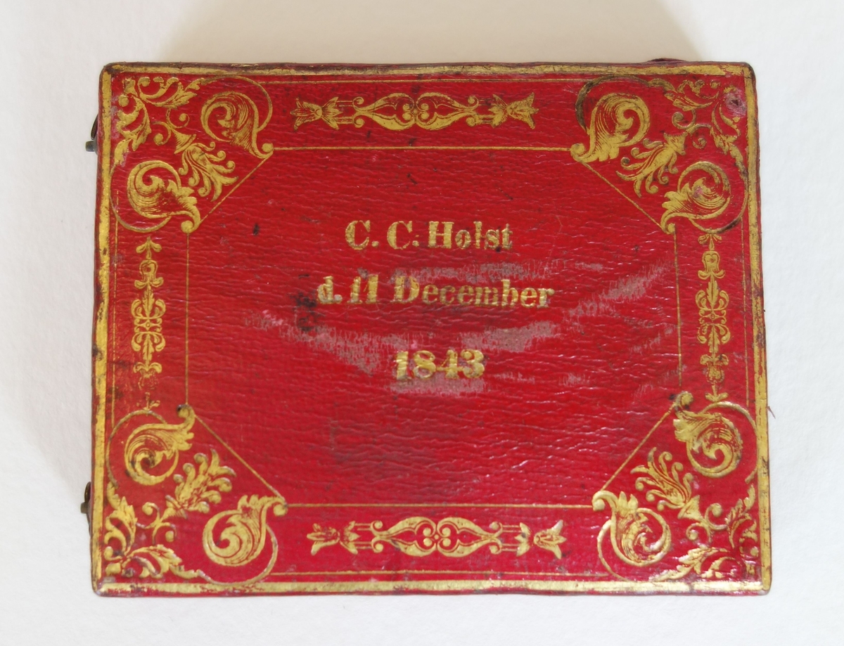 Rund medaljong. Ligger i rødt etui med gullpreg og påskriften C.C. Holst / d. 11 December / 1843. Etuiet og medaljongen hører opprinnelig ikke sammen. Mulig etuiet tilhører DM.05370