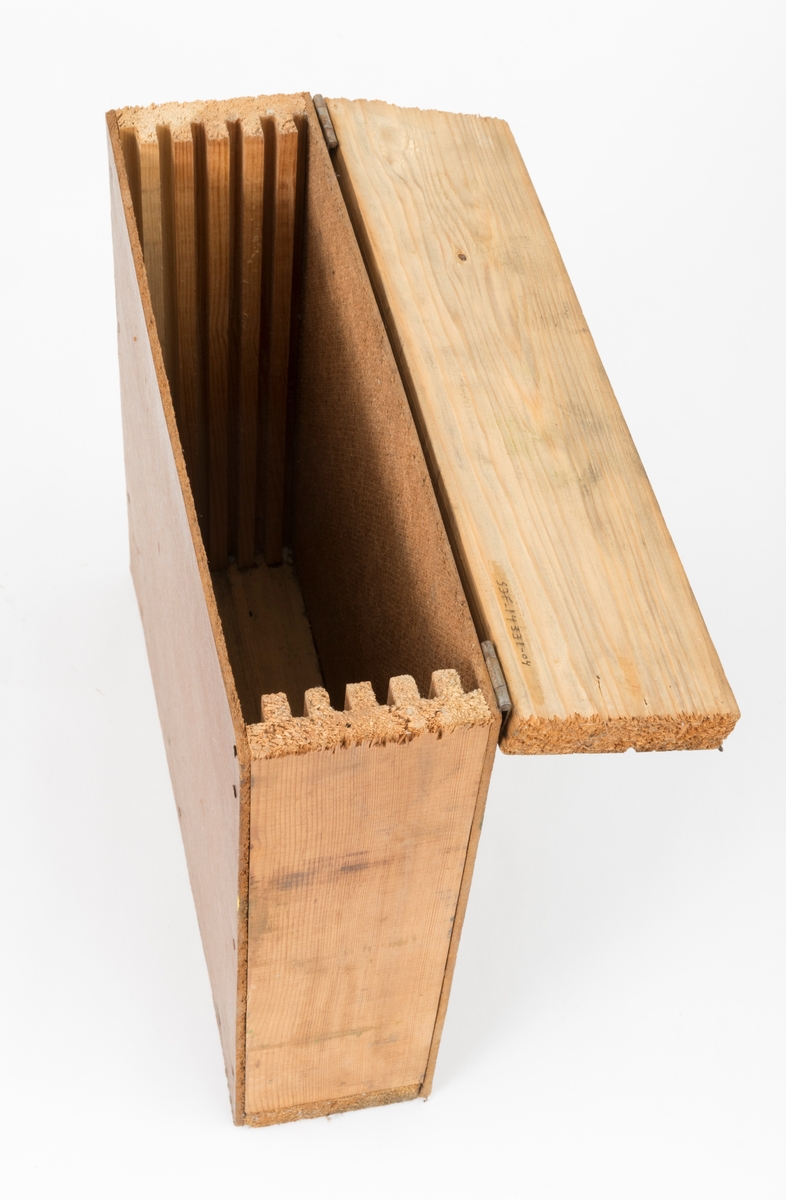 Gjenstanden er del av et sagbladsett som består av et treskrin, kassett, treeske, med 3 sirkesagblad beregnet for rydningssag av typen Brushking (Se SJF.14329). Dette skjemaet omhandler treskrinet, sagbladkassetten.   
Treskrinet består av to sidevegger med utføreste spor, hengslet lokk og bunn. Framside og bakside er laget av huntonittplater som er festet til sideveggene og bunn med små spikre. Lokket har en krok som kan klemmes inn under en spiker, slik at det sitter fast. Sagbladene som oppbevares i kassetten skyves inn på tilpassede riller, spor, i treesken. Treskrinet kan romme 6 sagblad.