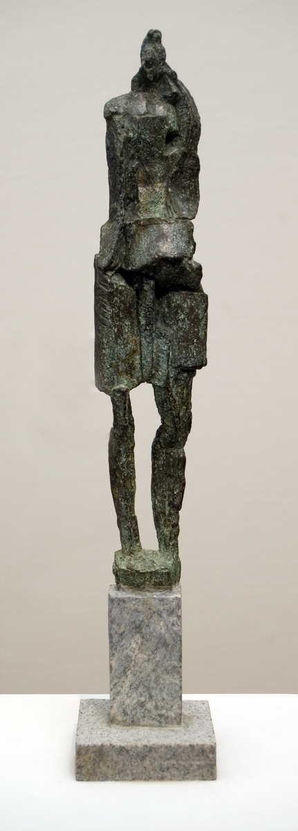 Skulptur "Kjolen" av Rune Rydelius, av brons på granitsockel. Smal figur i knälång kjol. Sockeln indelad i bred botten och smalare överdel.