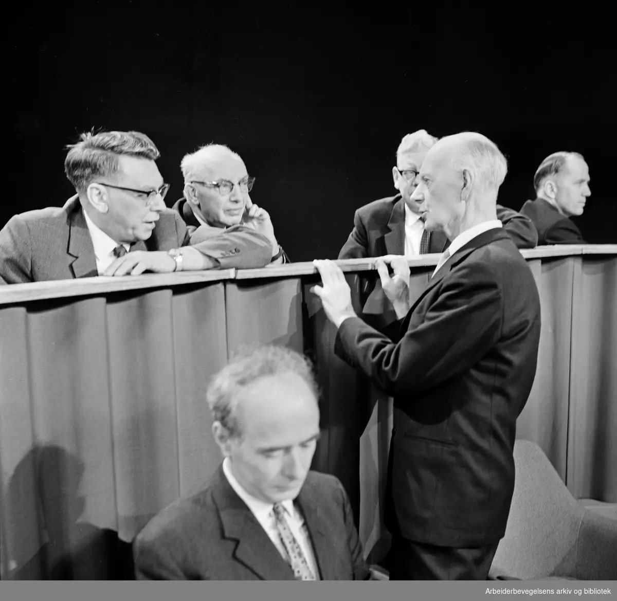 Valgdebatt i NRK - TV. Statsminister Einar Gerhardsen konfererer sine sekretærer Olav Brunvand, Olaf Solumsmoen og Dagfin Juel. I forgrunnen: Trygve Bratteli. I bakgrunnen til høyre: Lars Korvald. 25 februar 1965.