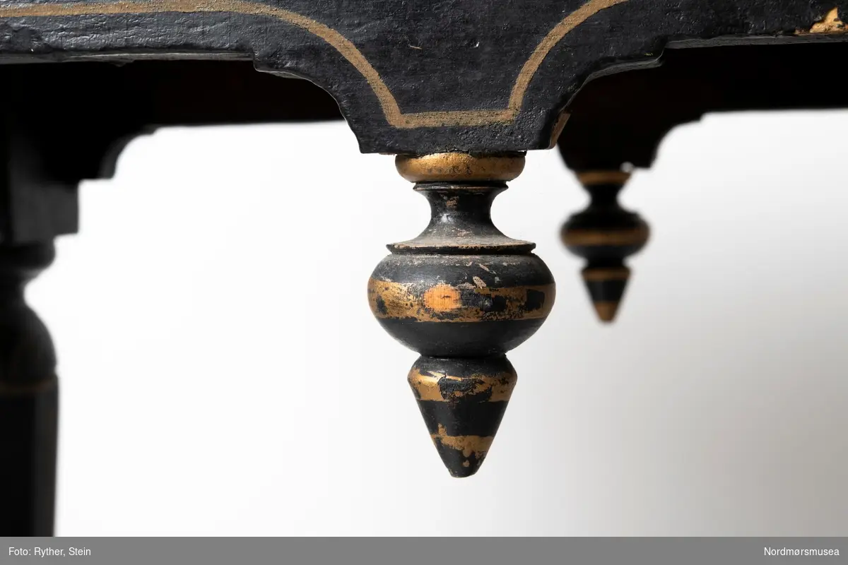 Et bord. ...Ved hvert hjørne f. utskårne menneskefigurer, muligens engler. Men vingene er borte. Grunnmalingen sort, forgylte streker og ornamenter langs platens rand. Malingen sannsynligvis i 1880-årene av Ranheimsæter.