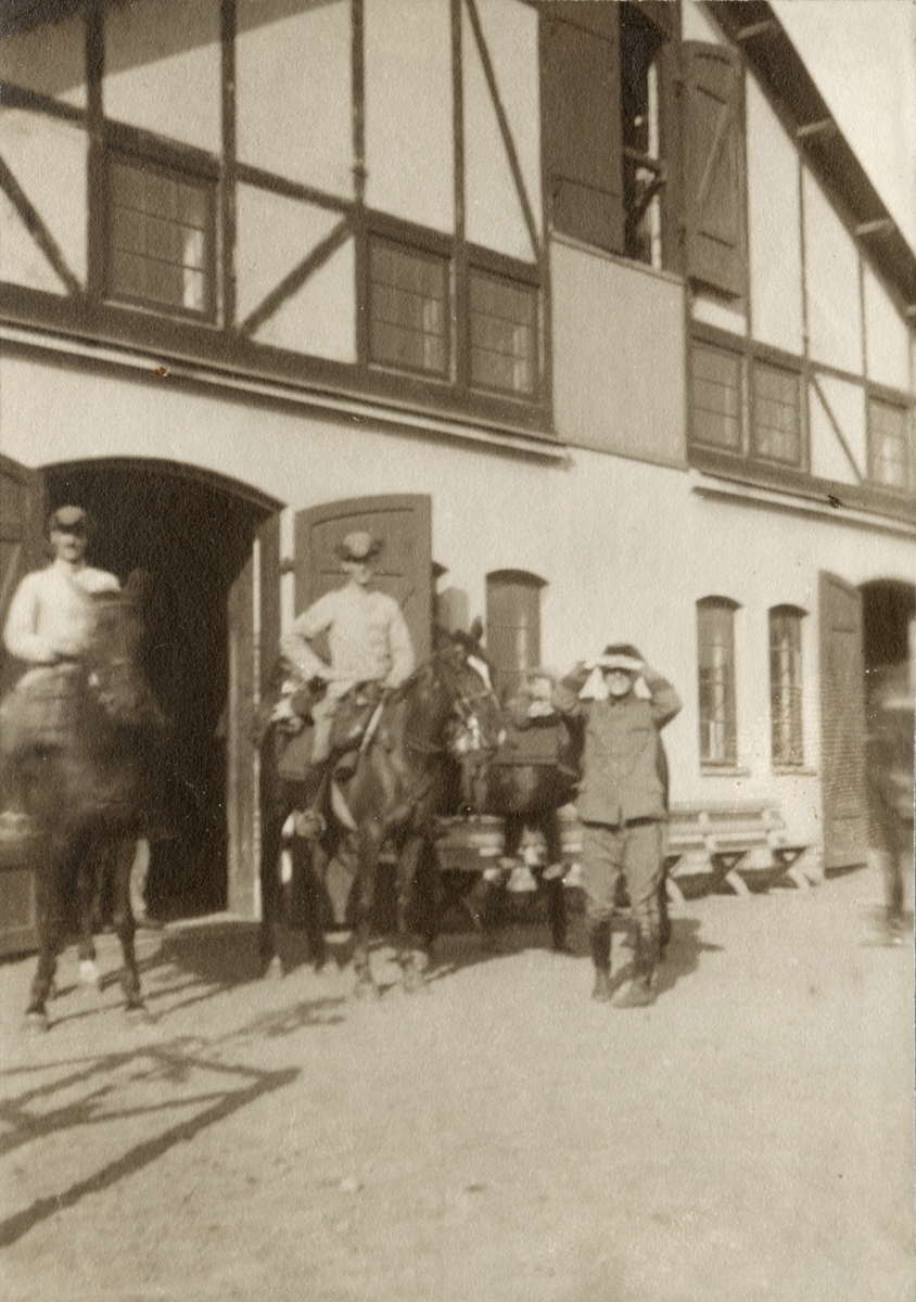 Soldater till häst framför stall.